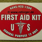 Ovaler Aufkleber mit der Aufschrift ‚FIRST AID KIT‘ und dem Esculabstab-Symbol sowie der Bezeichnung ‚U.S.‘ für US-Militärverbandskästen.